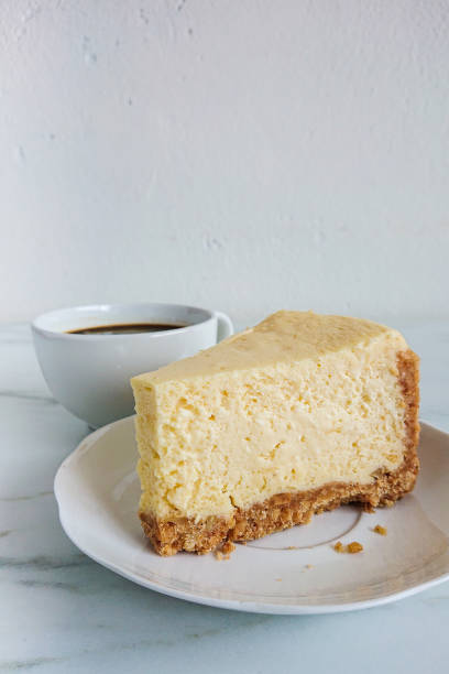 istock a peace of cheese cake and a cup of black coffee on light marble surface 1144478432