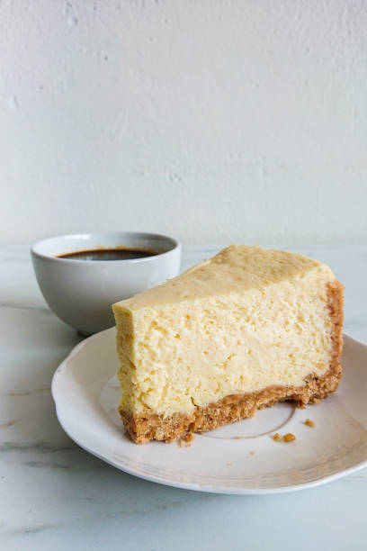 istock a peace of cheese cake and a cup of black coffee on light marble surface 1144478435