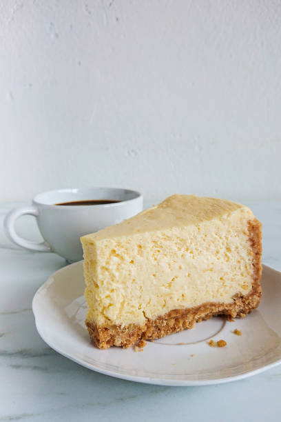 istock a peace of cheese cake and a cup of black coffee on light marble surface 1144478437