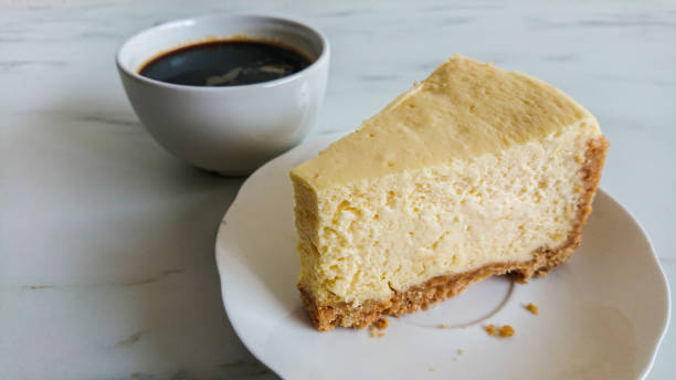 istock a peace of cheese cake and a cup of black coffee on light marble surface 1144478439