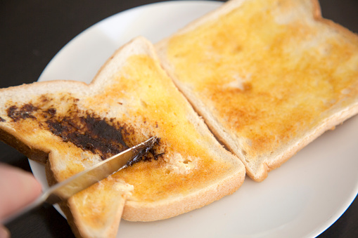 spreading yeast spread on white bread toast