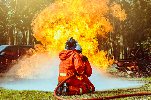 Firefighters fighting a fire operation, Water spray by high pressure nozzle to fire surround with smoke, Firefighters extinguish a house