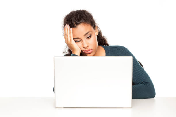 young african tired woman sitting at her desk in front of laptop on white background - one person people boredom isolated imagens e fotografias de stock