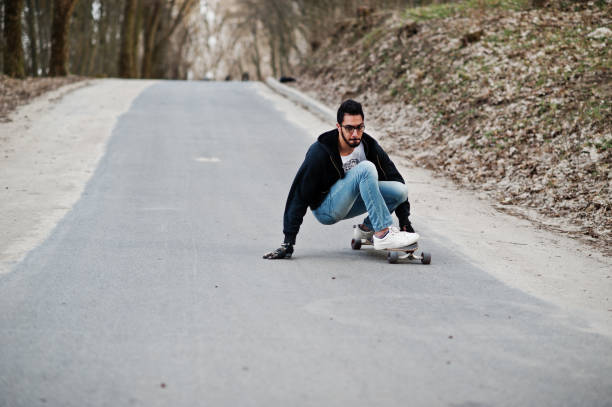 istock Street style arab man in eyeglasses with longboard 1144489893