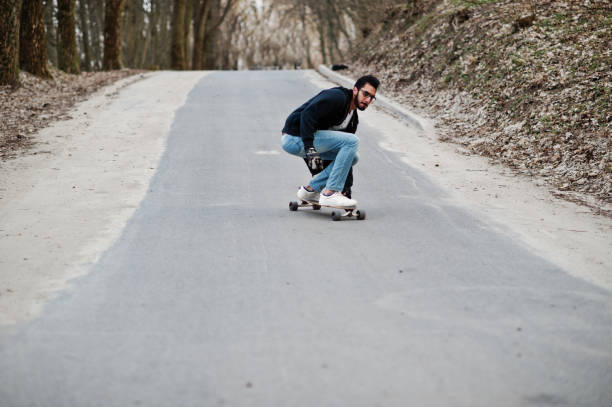istock Street style arab man in eyeglasses with longboard 1144489906