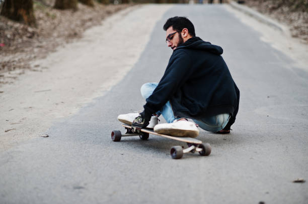 istock Street style arab man in eyeglasses with longboard 1144489930