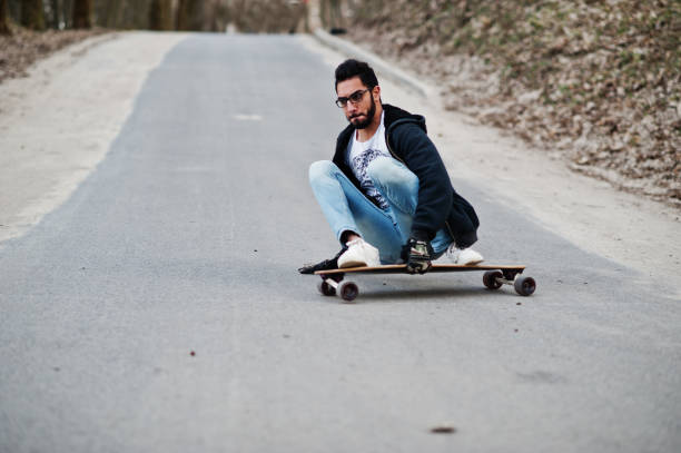 istock Street style arab man in eyeglasses with longboard 1144490030