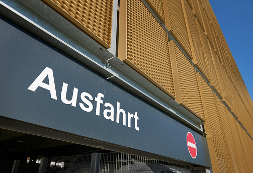 Wide angle lens photograph of an exit-sign at a new \nparking garage with golden shieldings. (Germany)