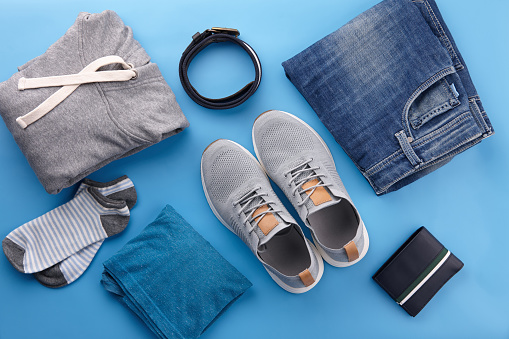 Mens summer casual clothing outfits and accessories flat lay on blue background, top view