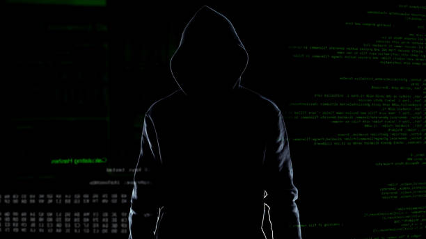 istock Silhouette of fearless male hacker standing on animated computer code background 1144493857