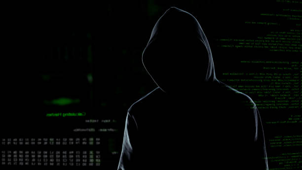 istock Faceless male hacker in hoodie standing in front of animated computer code 1144493912