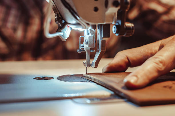 man sews leather on a sewing machine stock photo