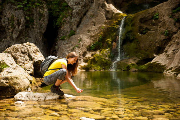 istock active young woman drinking water from a mountain creek on a warm spring day 1144497552