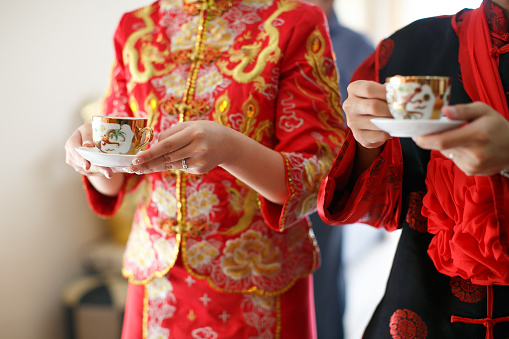Bride and Bridegroom in traditional wedding outfit holding tea cups on Chinese tea ceremony