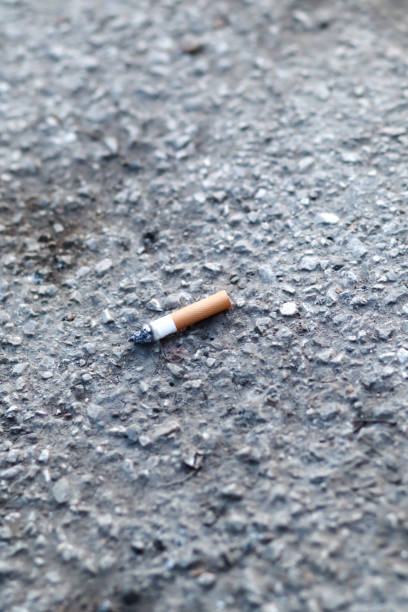 istock burning cigarette butt, single, isolated on concrete. Cigarette on pavement 1144502255