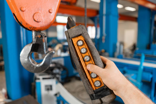 controle remoto do guindaste na produção. trabalhadores que trabalham com um guindaste no armazém.. a produção de ventilação e calhas. ferramenta e equipamento de dobra para chapa metálica. - industrial equipment automated business push button - fotografias e filmes do acervo