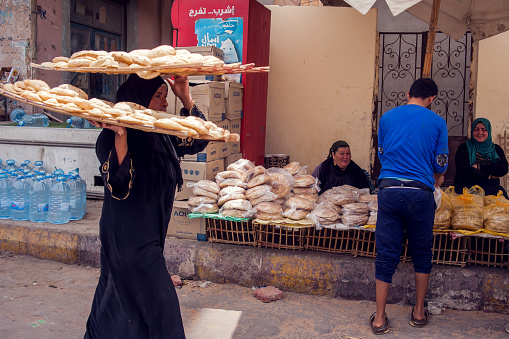 Woman carry bread on hand and on head, Egypt, Hurghada, 06.04.2019