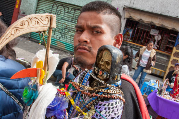 A young man carries a statue of the Santa Muerte cult along a street in the Tepito district of Mexico City Mexico City, Mexico, Nov 01 - The cult of the Holy Death in Mexico City and in the rest of the country has ancient origins, rooted in the Spanish conquest and in the autochthonous beliefs of the pre-Columbian civilizations. In the photo the pilgrimage of hundreds of faithful to the temple of the Holy Death in the Tepito district. muerte stock pictures, royalty-free photos & images