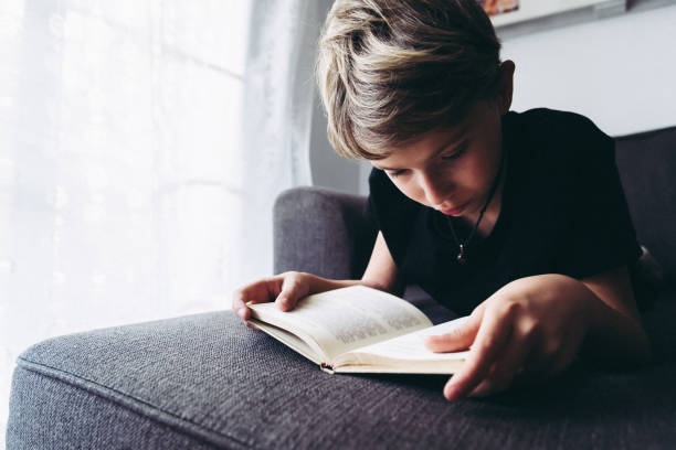 istock Boy Reading Book On Sofa At Home 1144510213