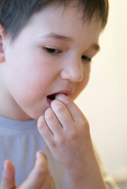 istock Boy Touching His Loose Tooth in His Mouth 1144514836