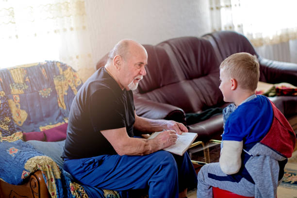 istock Little boy with broken arm doing homework with his grandfather 1144518318