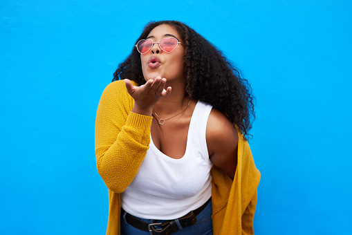 Studio portrait of an attractive young woman blowing a kiss against a blue background