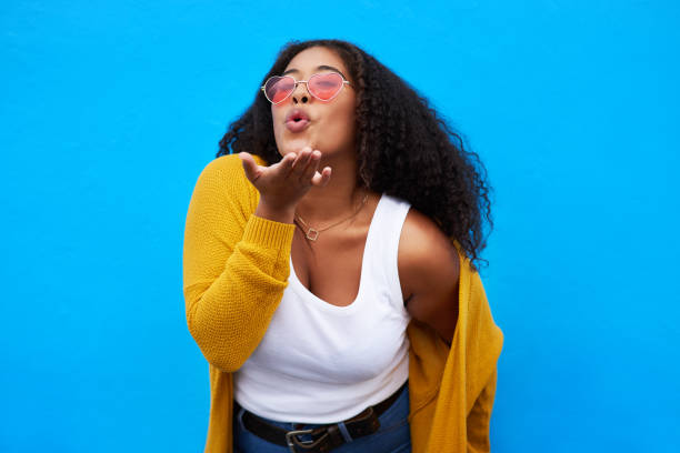 Blowing lots of love to you Studio portrait of an attractive young woman blowing a kiss against a blue background blowing a kiss stock pictures, royalty-free photos & images