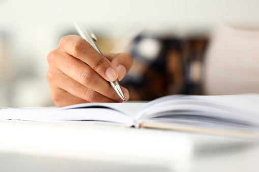 Arm of black woman write story in notebook preparing for college