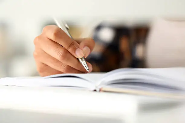 Photo of Arm of black woman write story in notebook