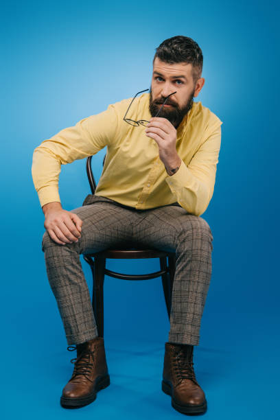 istock handsome bearded man sitting on chair isolated on blue 1144520335