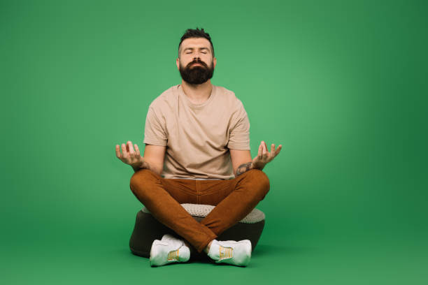 istock Handsome bearded man meditating and sitting on green 1144520393