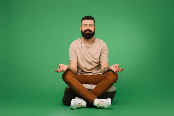 istock Happy bearded man meditating and sitting on green 1144520404
