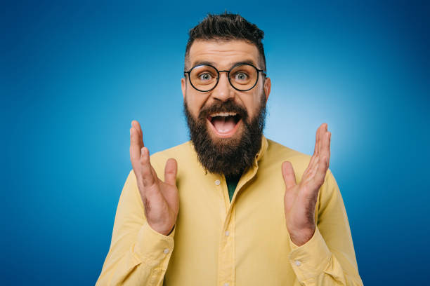 istock excited bearded man in eyeglasses gesturing isolated on blue 1144521029
