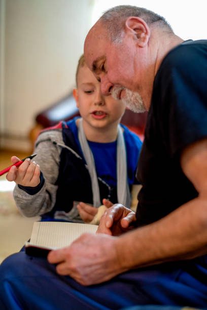 istock Little boy with broken arm doing homework with his grandfather 1144521319