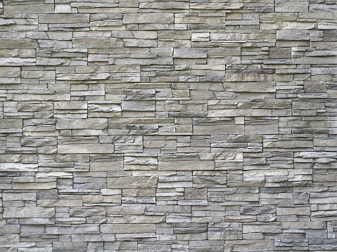 Stone cladding wall made of  striped stacked slabs of natural gray rocks. Panels for exterior.