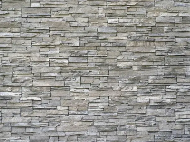 Photo of Stone cladding wall made of  striped stacked slabs of natural gray rocks. Panels for exterior.
