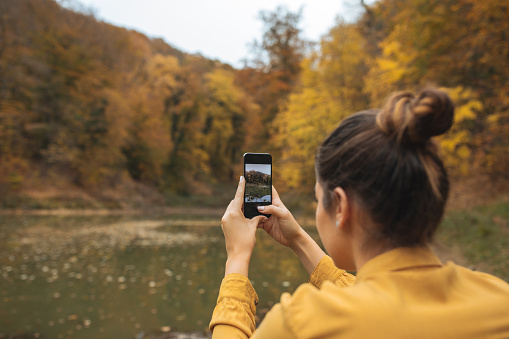Young woman taking picture with cellphone in nature