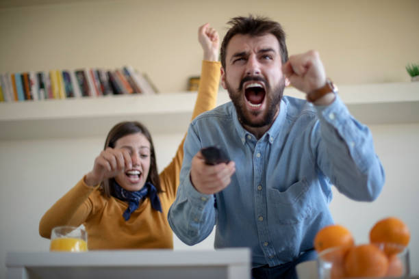 istock Young couple watching soccer game and celebrating 1144524504