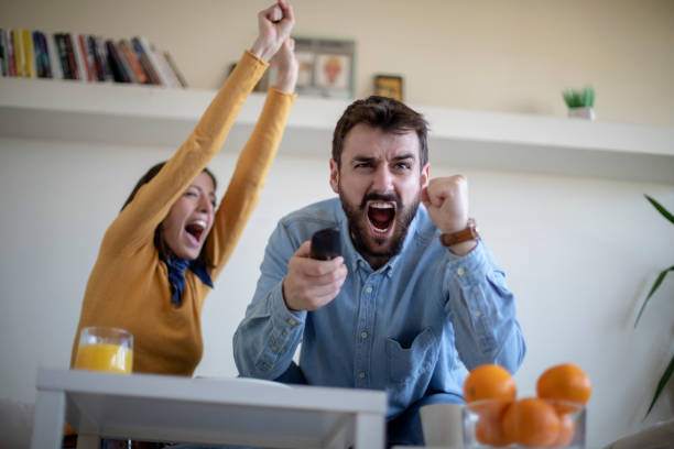 istock Young couple watching soccer game and celebrating 1144524549