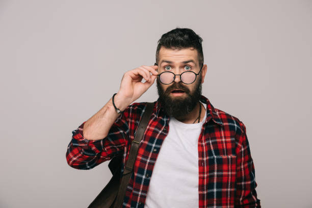 istock surprised handsome man holding eyeglasses, isolated on grey 1144525383
