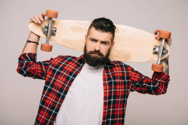 istock handsome bearded man in checkered shirt posing with longboard isolated on grey 1144525440