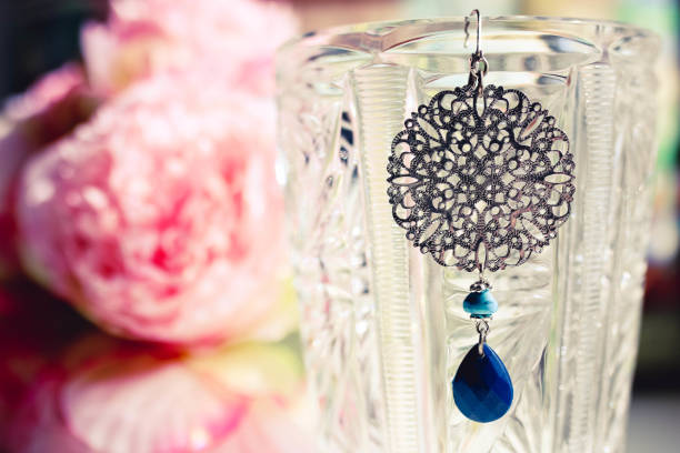 istock Ladies earring whith blue stone close up with colorful flowered background. Female concept. 1144525607