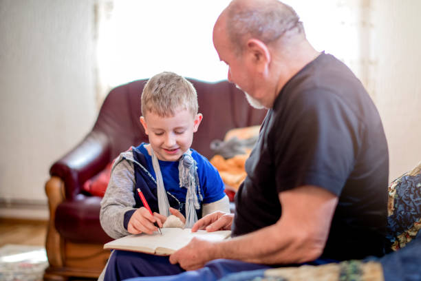 istock Little boy with broken arm doing homework with his grandfather 1144526520
