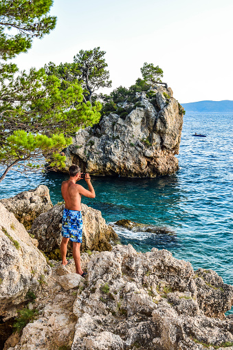 The man photographs the rock Brela. Punta Rata Beach, Croatia.