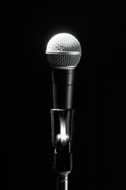 istock Black modern microphone on stand, black dark background. Accentuated shapes with light. 1144533036