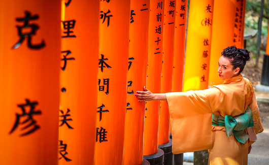 29 march 2019 - Kyoto, Japan: Tourist woman dressed with kimono touching a torii in Fushimi inari Taisha shrine