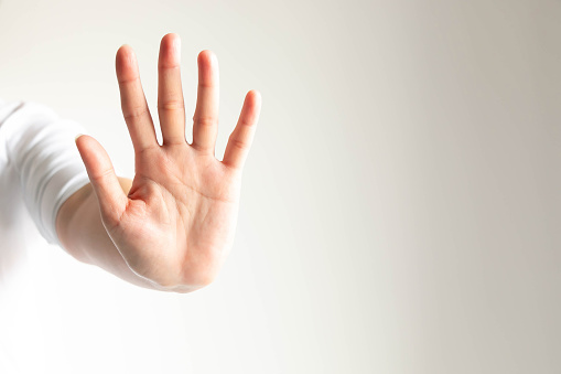 A hand signs raise arm and showing a palm with five fingers meaning dont or stop on white background.