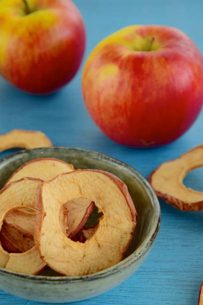 istock Fruit healthy snack, dehydrated apple ring chips with fresh red apples on blue background 1144536423