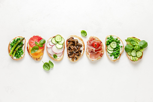 Culinary background with assortment of toasts lying in line, view from above, blank space for a text