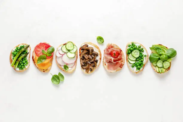 Culinary background with assortment of toasts lying in line, view from above, blank space for a text